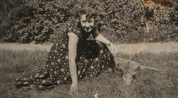  "Olga Niewska, w letniej sukience, na polanie, obok leżącego koziołka."  