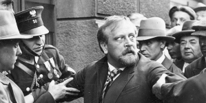 Bogusław Samborski jako kasjer Hieronim Śpiewankiewicz ( trzymany przez policjantów) w jednej ze scen filmu „Niebezpieczny romans”.