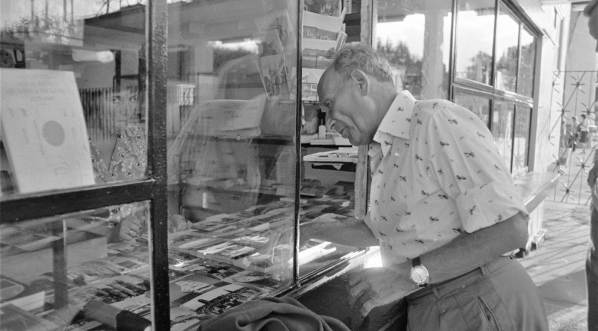 Pisarz Julian Stryjkowski stoi przy kiosku z pocztówkami, sierpień 1975 r.  